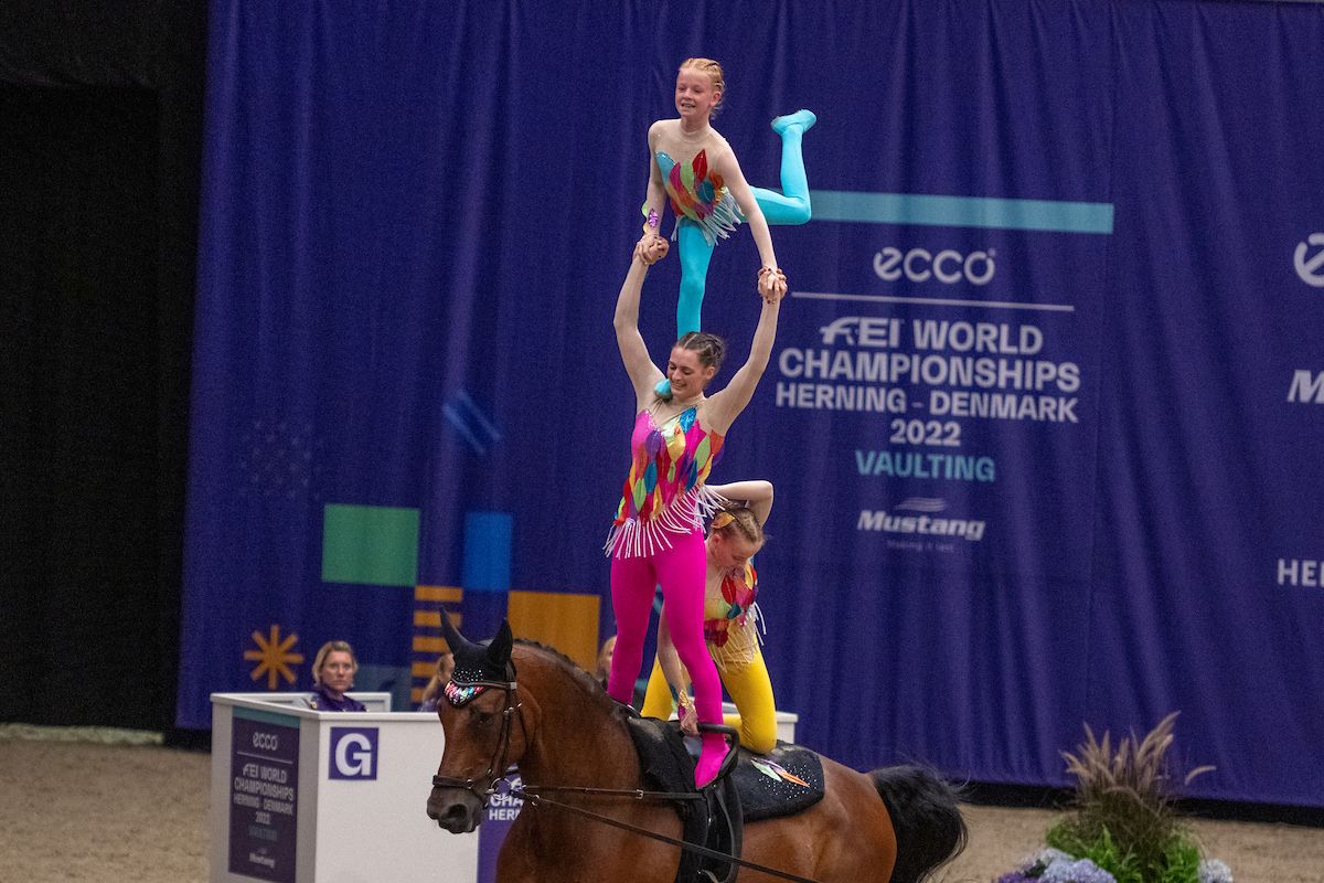 British team in colourful outfits on a vaulting horse at the FEI World Championships 2022.
